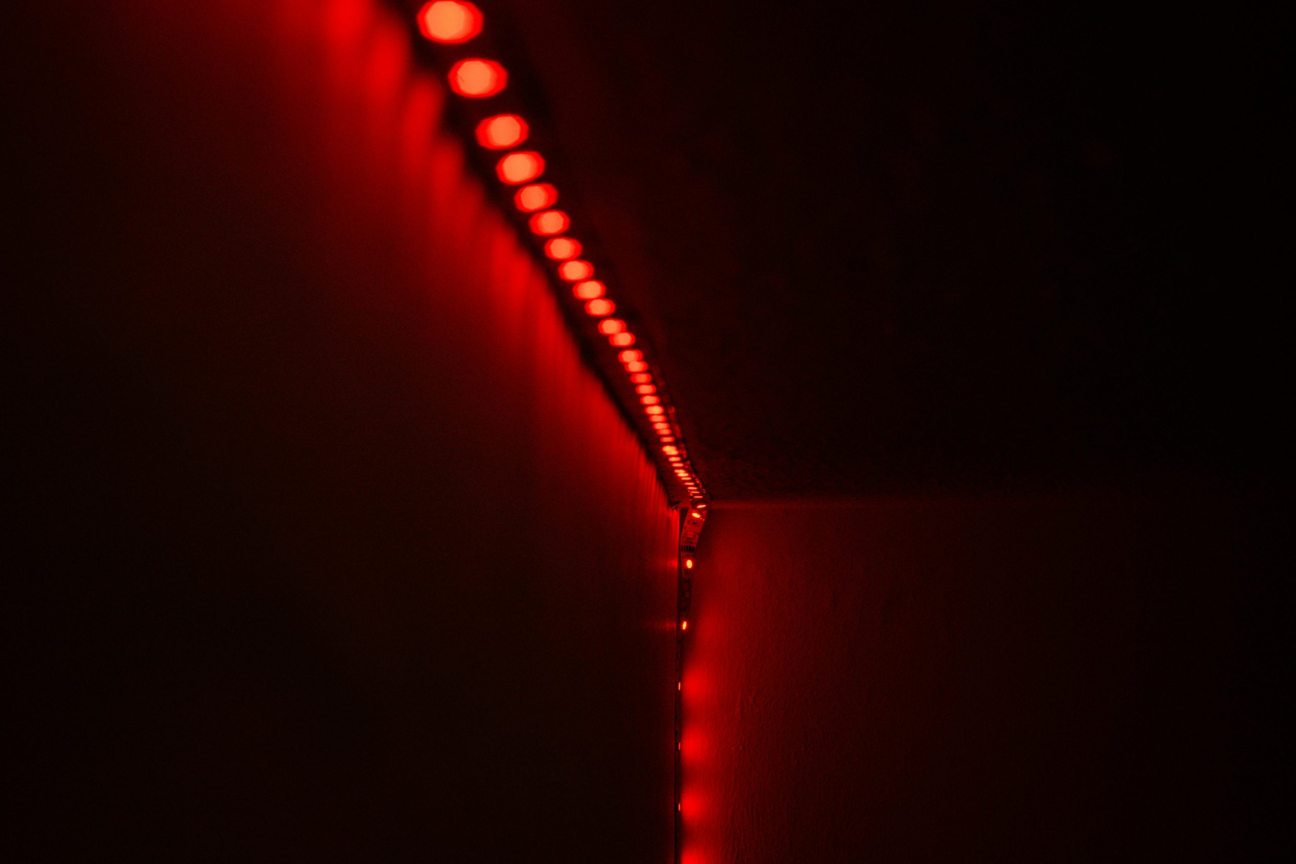 about-03 Close-up of red LED strip lights illuminating a dark room, creating a moody atmosphere.