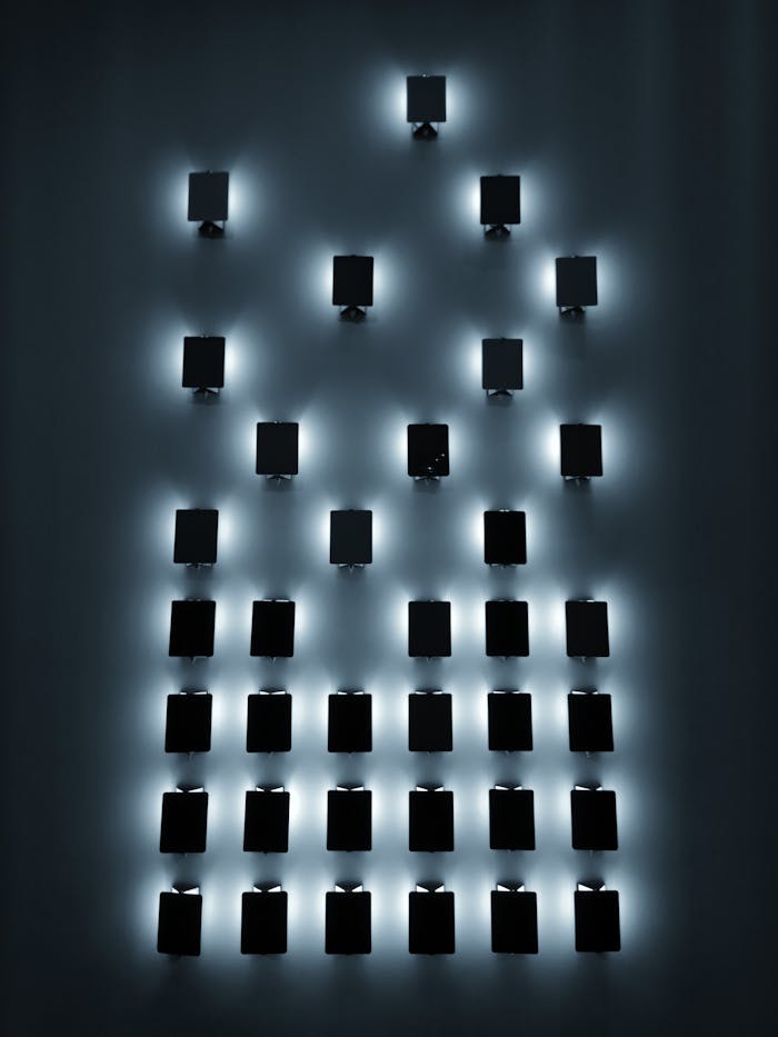about-04 Rows of small black rectangular glowing luminaries on wall in dark room at night